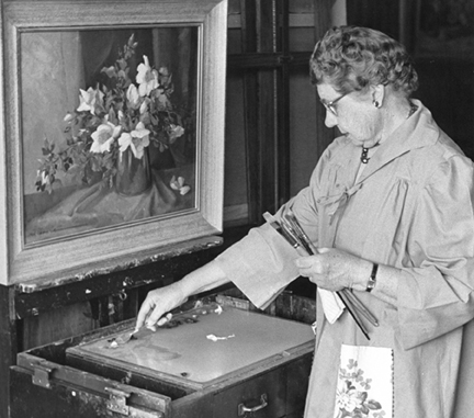 Nell Walker Warner at her easel painting a floral