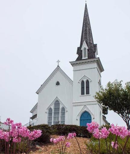 Mendocino Presbyterian Church pictured here with "naked ladies" in bloom in front ot the church.