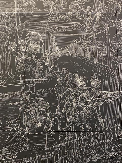 Adolph Hitler to Vietnam, the effects of war, those who wage war and those victims who pay the price. To the right,  "Arbeit Macht Frei" ("Work makes you free") sign at the entrance of Auschwitz.. Below this, the terrorized faces of a Vietnamese family with a Vietnam War era Huey helecopter gunship in the background. 